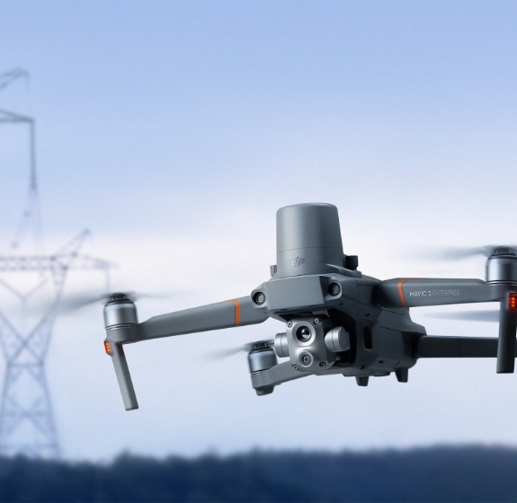 Drohne, die vor dem Hintergrund von Himmel und Hochspannungsnetz in der Luft schwebt