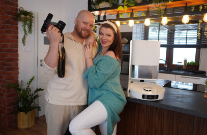 ein Paar in der Küche und daneben auf dem Tresen ein Reinigungsroboter