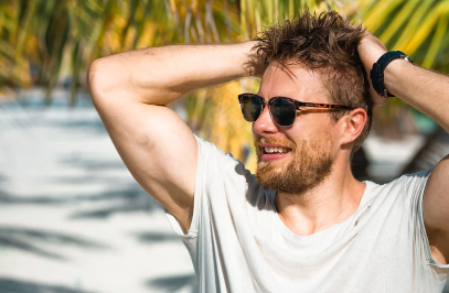 Mann mit Sonnenbrille sitzt unter Palmen